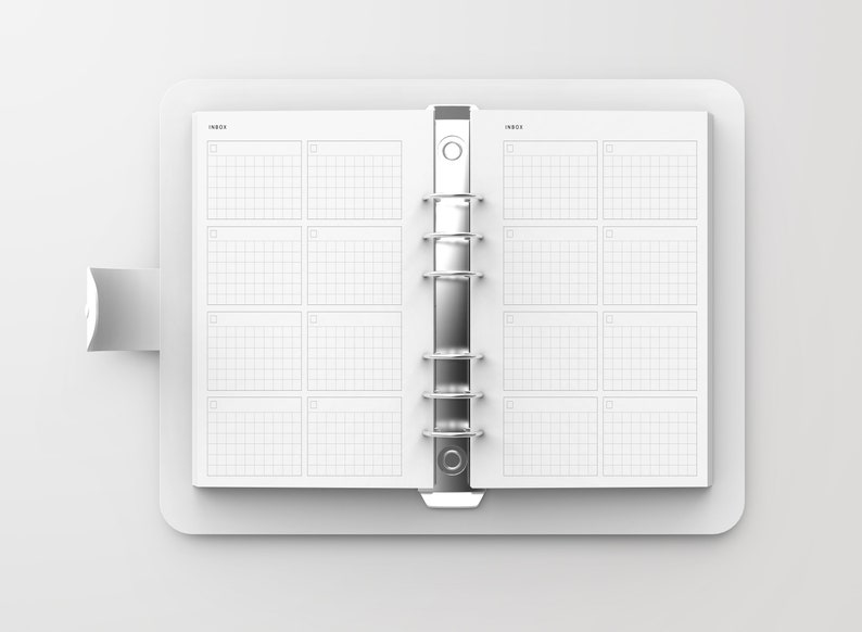 May include: A white, closed, ring-bound planner with a gridded layout. The planner has a white cover and a silver binding.