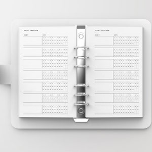 Puede incluir: Un rastreador de h&aacute;bitos blanco con un encuadernador plateado. El rastreador tiene dos p&aacute;ginas con las palabras "Habit Tracker" en la parte superior de cada p&aacute;gina. Las p&aacute;ginas est&aacute;n divididas en secciones para "H&aacute;bitos" y "D&iacute;as". La secci&oacute;n "D&iacute;as" tiene una cuadr&iacute;cula de n&uacute;meros del 1 al 31.