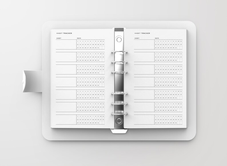 Puede incluir: Un rastreador de h&aacute;bitos blanco con un encuadernador plateado. El rastreador tiene dos p&aacute;ginas con las palabras "Habit Tracker" en la parte superior de cada p&aacute;gina. Las p&aacute;ginas est&aacute;n divididas en secciones para "H&aacute;bitos" y "D&iacute;as". La secci&oacute;n "D&iacute;as" tiene una cuadr&iacute;cula de n&uacute;meros del 1 al 31.