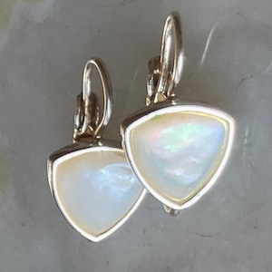 May include: A pair of silver-toned earrings with a triangular, iridescent, pearlescent stone set in a silver frame. The earrings have a lever-back closure. The earrings are designed for pierced ears.