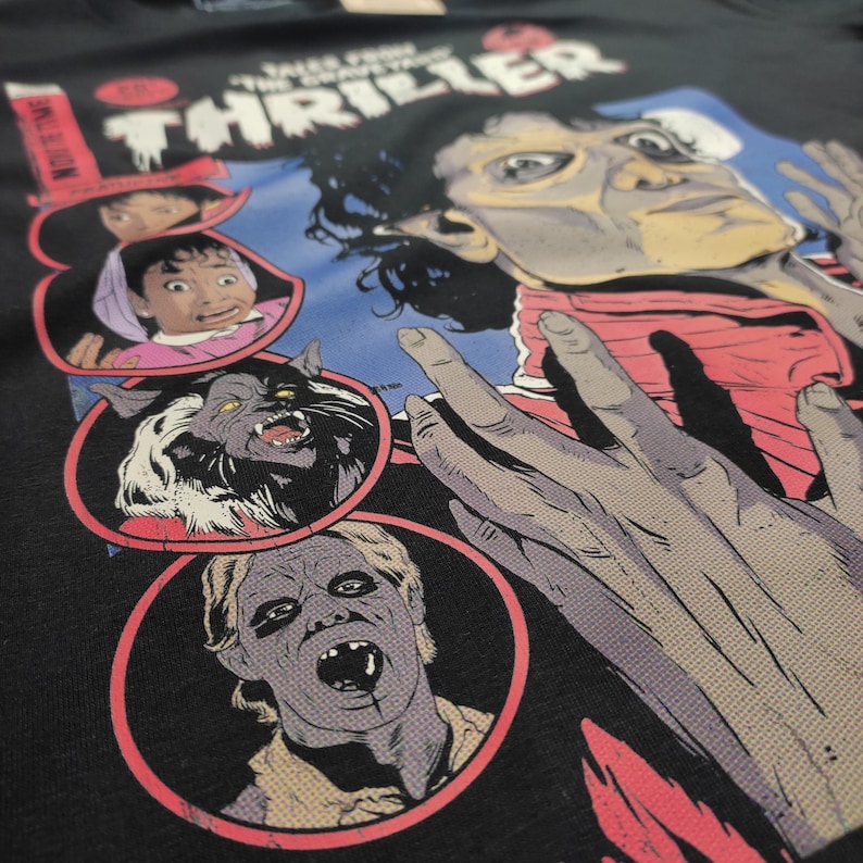 May include: A black t-shirt with a graphic print of Michael Jackson from the "Thriller" music video. The graphic features a red and black comic book style illustration of Michael Jackson with a werewolf, a zombie, and a child.