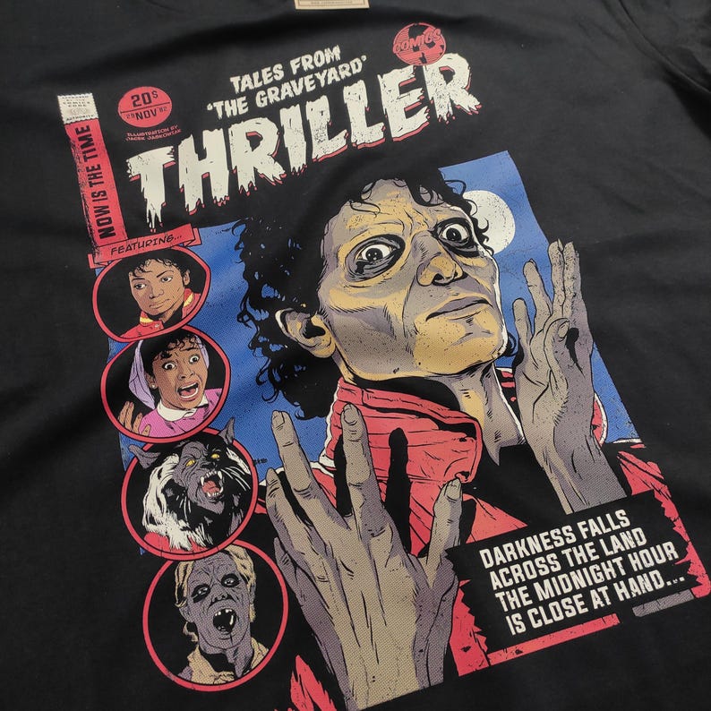 May include: A black t-shirt with a comic book style graphic featuring a zombie Michael Jackson with the text "Thriller" and "Tales from 'The Graveyard'" above him. The graphic also includes a werewolf, a woman with a shocked expression, and a man with a shocked expression.