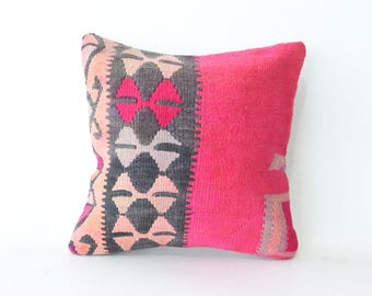 May include: A pink and gray patterned throw pillow with a geometric design. The pillow is made of a soft, woven fabric.