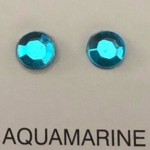 May include: Two round, aqua blue rhinestones on a white background. The text "AQUAMARINE" is printed below the rhinestones.