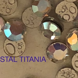 May include: Close-up of a variety of clear iridescent rhinestones with the text "CRYSTAL TITANIA" visible in the image.