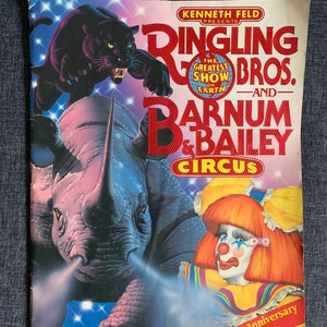 May include: A vintage program for the Ringling Bros. and Barnum & Bailey Circus, featuring a black panther on a rhinoceros and a clown with a red nose and colorful makeup. The program is for the 120th anniversary edition.
