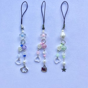 May include: Three phone charms with different colored beads and charms. The charms are made with white, pink, blue, and green beads. The charms include a cloud, a Hello Kitty character, and a star.