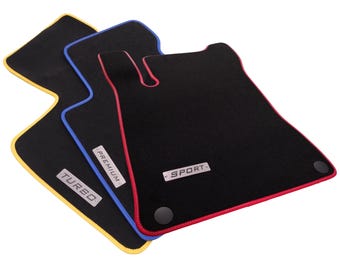Op de afbeelding: Drie zwarte automatten met opvallende gekleurde randen in geel, blauw en rood. Elke mat is voorzien van een rechthoekig metalen plaatje met de tekst TURBO, PREMIUM of SPORT en bevat ronde zwarte bevestigingspunten voor een veilige installatie.