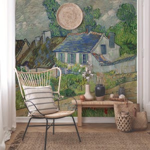 Puede incluir: Una casa blanca con contraventanas azules y un techo verde se representa en un estilo de pintura que recuerda a Vincent van Gogh. La casa está rodeada de árboles y flores, y el cielo es azul claro con nubes blancas. La pintura está en una pared en una habitación con una silla blanca y una mesa de madera.