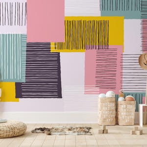 May include: A colorful wall mural with geometric shapes in pink, yellow, teal, and purple. The design includes vertical and horizontal lines. The room features a woven ottoman, a wooden coat rack with hats, and storage bins.