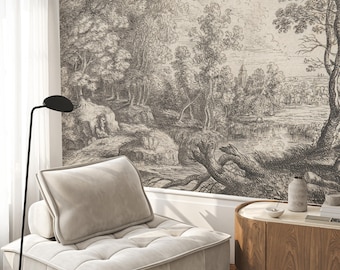 Op de afbeelding: Een zwart-witte gravure van een boslandschap met een rivier en een stad in de verte. De gravure is gedrukt op een beige achtergrond en wordt omlijst door een witte muur. Een witte bank met een zwarte lamp staat op de voorgrond.