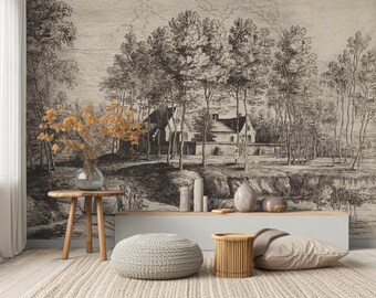 Op de afbeelding: Een zwart-witte vintage illustratie van een huis en bomen. De illustratie is gedrukt op een behangmuurschildering en wordt getoond in een woonkamer met een tapijt, een poef en een bijzettafel.