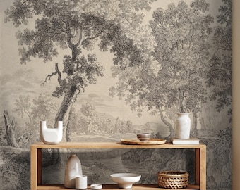 Op de afbeelding: Een zwart-witte vintage illustratie van een bos scène met twee bomen, een rivier en een klein dorp in de verte. De illustratie is gedrukt op behang en wordt weergegeven op een houten plank met decoratieve vazen, een kom en een mand.