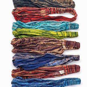 May include: A stack of eight colorful headbands in various shades, including black, red, teal, yellow-green, and blue. Each headband has a textured, crinkled fabric and an elastic band for a comfortable fit. The headbands are displayed on a white background.