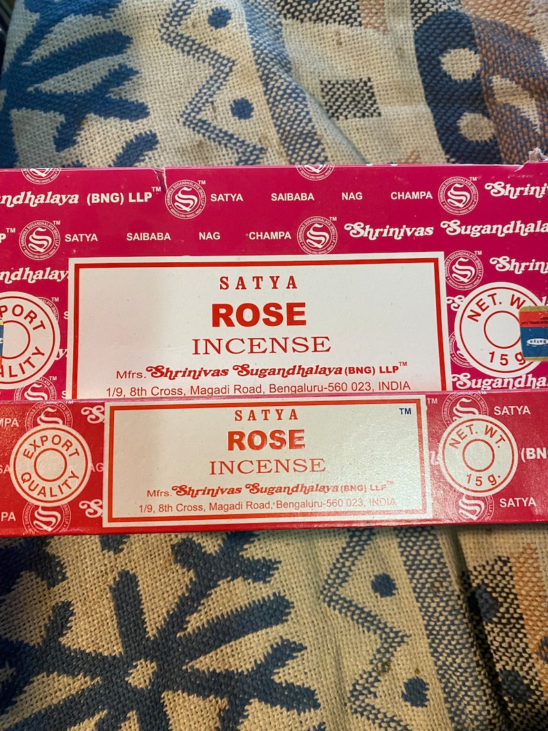 May include: A red and white box of Satya Rose incense sticks. The box features the brand name "Shrinivas Sugandhalaya" and the text "Satya Rose Incense". The box is 15 grams.