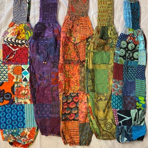 May include: Five pairs of colorful patchwork pants with elastic waistbands. The pants are made of different fabrics and patterns, including floral, geometric, and paisley.