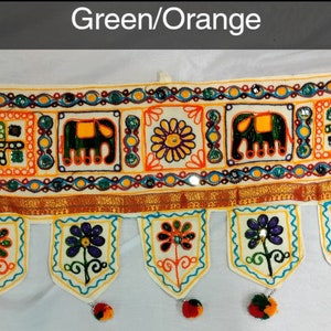 May include: A white fabric door hanging with colorful embroidery featuring elephants, flowers, and geometric patterns. The hanging has a green and orange color scheme and is decorated with beads and sequins.