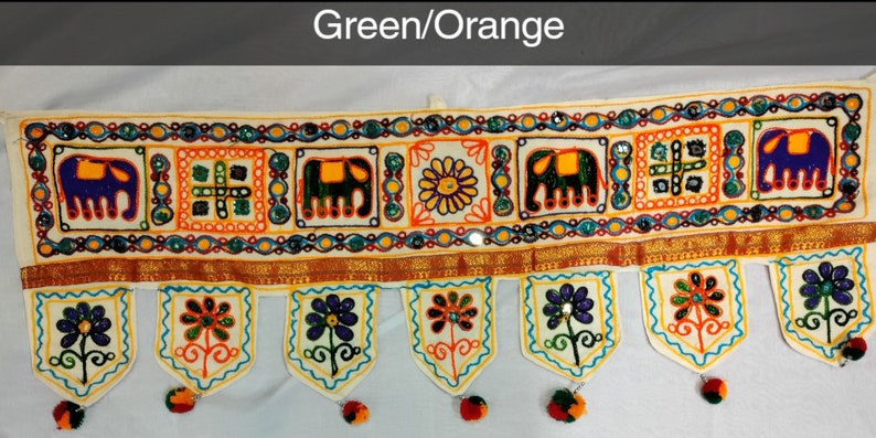May include: A white fabric door hanging with colorful embroidery featuring elephants, flowers, and geometric patterns. The hanging has a green and orange color scheme and is decorated with beads and sequins.