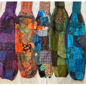 May include: Five pairs of colorful patchwork pants with elastic waistbands. The pants are made of different fabrics and patterns, including floral, geometric, and paisley.