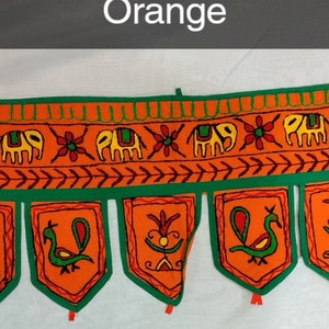 May include: Orange and green fabric door hanging with embroidered elephants, peacocks, and flowers. The hanging has a scalloped bottom edge with tassels.