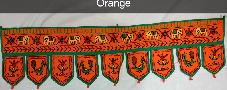 May include: Orange and green fabric door hanging with embroidered elephants, peacocks, and flowers. The hanging has a scalloped bottom edge with tassels.