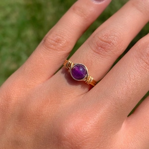 May include: A gold wire wrapped ring with a purple amethyst gemstone.