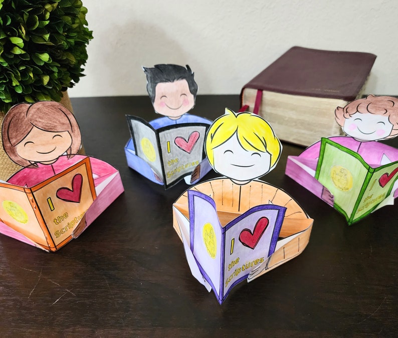May include: Four paper craft figures of people reading books. Each figure has a different colored shirt and a book with the words "I love the Scriptures" on the cover. The books are different colors and have a heart on the cover.