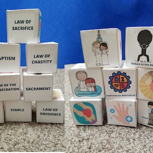 May include: A set of white cubes with black text and illustrations. The cubes feature phrases like "Law of Sacrifice", "Baptism", "Law of Chastity", "Sacrament", "Law of the Gospel", "Temple", "Law of Obedience", "Endure to the End", "Stand as a Witness", "Dedicate our Resources".