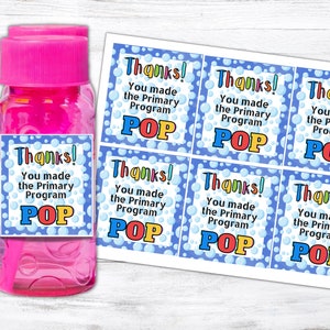Könnte beinhalten: Sechs blaue und weiße Dankeschön-Etiketten mit bunten Blasen und dem Text "Danke! Sie haben das Grundschulprogramm POP gemacht" auf jedem Etikett. Die Etiketten sind an einer rosa Flasche mit Blasenlösung befestigt.