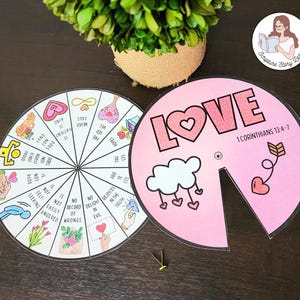 May include: Two circular educational tools with the word "LOVE" and "1 Corinthians 13:4-7" printed on one, and a list of virtues on the other. The tools are pink and white with illustrations and text. A small brass fastener is included.