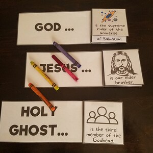 May include: A set of three white cards with black text. The first card says "GOD..." and the second card says "JESUS..." and the third card says "HOLY GHOST..." Each card has a corresponding card with a description. The first card's description says "is the supreme ruler of the universe. of Salvation." The second card's description says "is our elder brother." The third card's description says "is the third member of the Godhead."