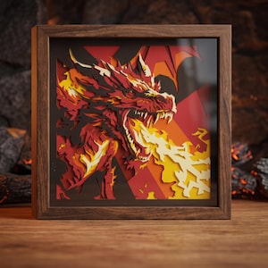 Könnte beinhalten: Ein quadratischer Holzrahmen mit einem mehrschichtigen Papierkunstwerk, das einen feuerspeienden Drachen darstellt. Der Drache ist in Rot-, Orange-, Gelb- und Schwarztönen gehalten, wobei komplexe Ausschnitte Tiefe und eine dynamische Textur erzeugen.