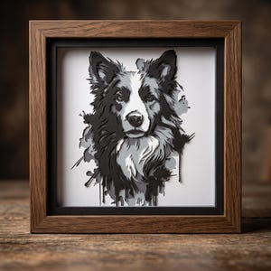 May include: A layered paper art piece featuring a black, white, and gray portrait of a Border Collie dog. The artwork is encased in a square, dark brown wooden frame with a black mat, creating a dimensional effect with sharp, cut-out edges.