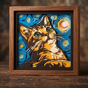May include: A multi-layered paper art piece in a wooden frame featuring an orange tabby cat with green eyes looking upward. The background consists of swirling blue and yellow patterns resembling a night sky with a crescent moon.