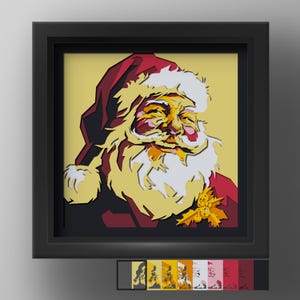 May include: A layered paper art piece featuring a stylised portrait of Santa Claus in a black shadow box frame. The artwork uses shades of red, white, yellow, and gold to depict Santa with a beard, hat, and holly leaves on a light yellow background.