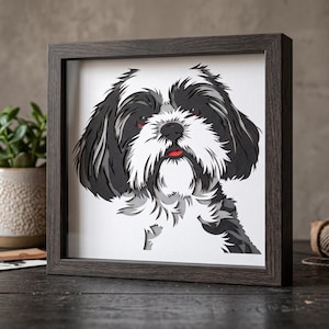 以下が含まれることがあります： 長い毛並みの白黒の犬を描いたレイヤードペーパーアートの肖像画で、ダークブラウンの正方形の木製フレームに入っています。白い背景に、白い鼻先、暗い色の耳、そして小さな赤い舌が見える犬のデザインです。