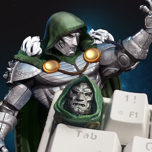 May include: A green and silver action figure of Doctor Doom, a Marvel Comics supervillain, is shown on a keyboard with the Tab key visible. The figure is wearing a green cape and a silver mask.