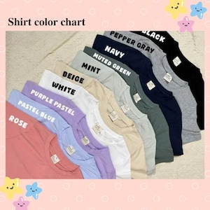 Puede incluir: Una carta de colores que muestra una variedad de camisetas en diferentes colores. Los colores incluyen rosa, azul pastel, pastel p&uacute;rpura, blanco, beige, menta, verde apagado, azul marino, gris pimienta y negro. El texto "Tabla de colores de camisetas" est&aacute; en la parte superior.