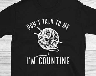 May include: Black t-shirt with white text that reads "Don't talk to me I'm counting" and a graphic of a ball of yarn with knitting needles.