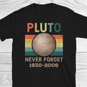 May include: Black t-shirt with a vintage-style graphic of Pluto, the dwarf planet. The graphic features a brown and white illustration of Pluto with the text "PLUTO NEVER FORGET 1930-2006".