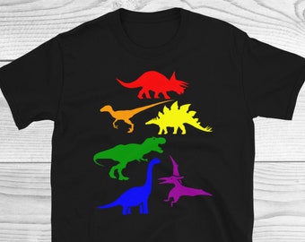 May include: Black t-shirt with a rainbow design featuring different dinosaurs. The dinosaurs are in a line, with the largest at the top and the smallest at the bottom. The dinosaurs are all facing to the right.