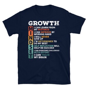 May include: Navy blue t-shirt with a white graphic that says "GROWTH MINDSET" and lists the benefits of having a growth mindset. The graphic is in a vintage style with a rainbow color scheme.