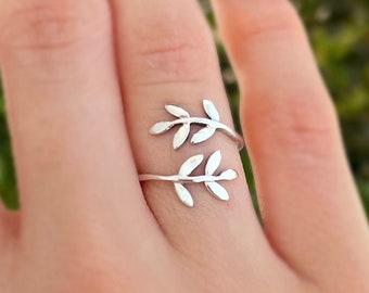 May include: A silver ring with a delicate leaf design. The ring is adjustable and can be worn on any finger.