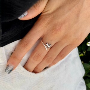 May include: A silver ring with a delicate leaf design. The ring is wrapped around the finger and has a simple, elegant style.