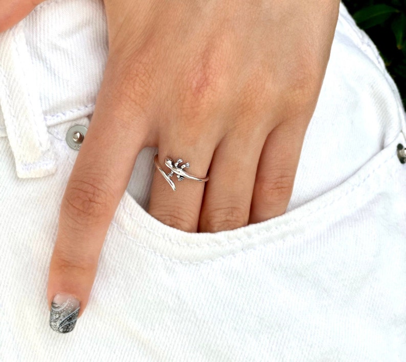 May include: A silver ring with a lizard design. The ring is wrapped around the finger and the lizard is facing to the right.