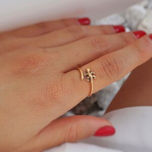 May include: Gold ring with a small lizard design. The ring is wrapped around the finger.