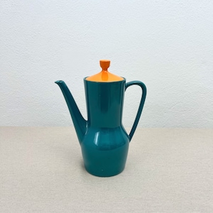 Könnte beinhalten: Eine teelfarbene Teekanne aus Keramik mit einem orangefarbenen Deckel. Die Teekanne hat einen runden Körper und einen Ausguss an der Seite.