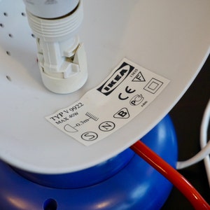 May include: A white lamp with a blue base and a white cord. The lamp has a white socket and a label that reads "IKEA" and "TYP V 9922 MAX 40W 0.3m".