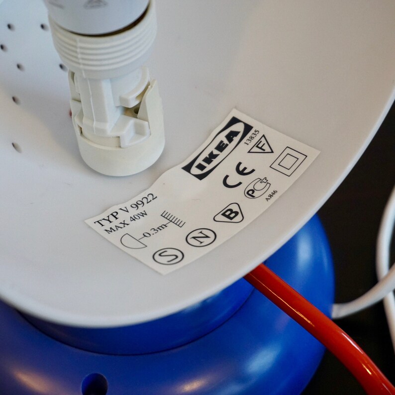 May include: A white lamp with a blue base and a white cord. The lamp has a white socket and a label that reads "IKEA" and "TYP V 9922 MAX 40W 0.3m".