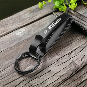 May include: Black leather key chain with a metal ring and a clip. The keychain is engraved with the text "Lt. Williams".